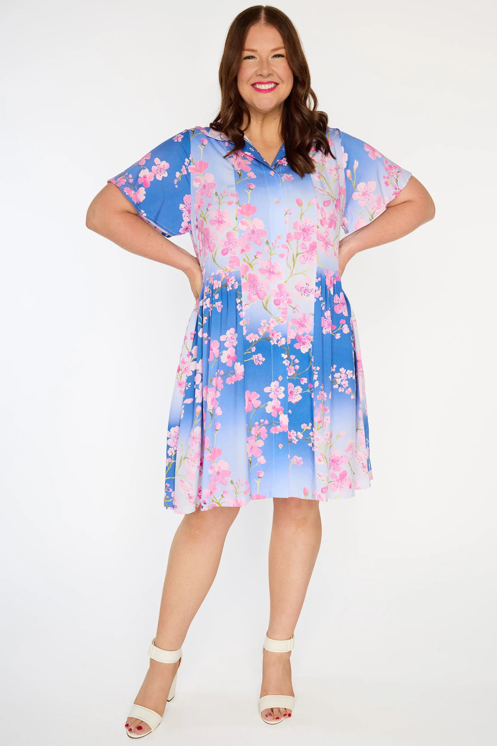 Woman wearing a blue dress with pink floral pattern on a white background