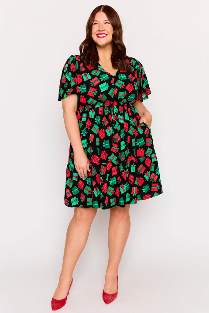 Angled Front View – Remi dress in Christmas Presents print, white base with red and green gifts
