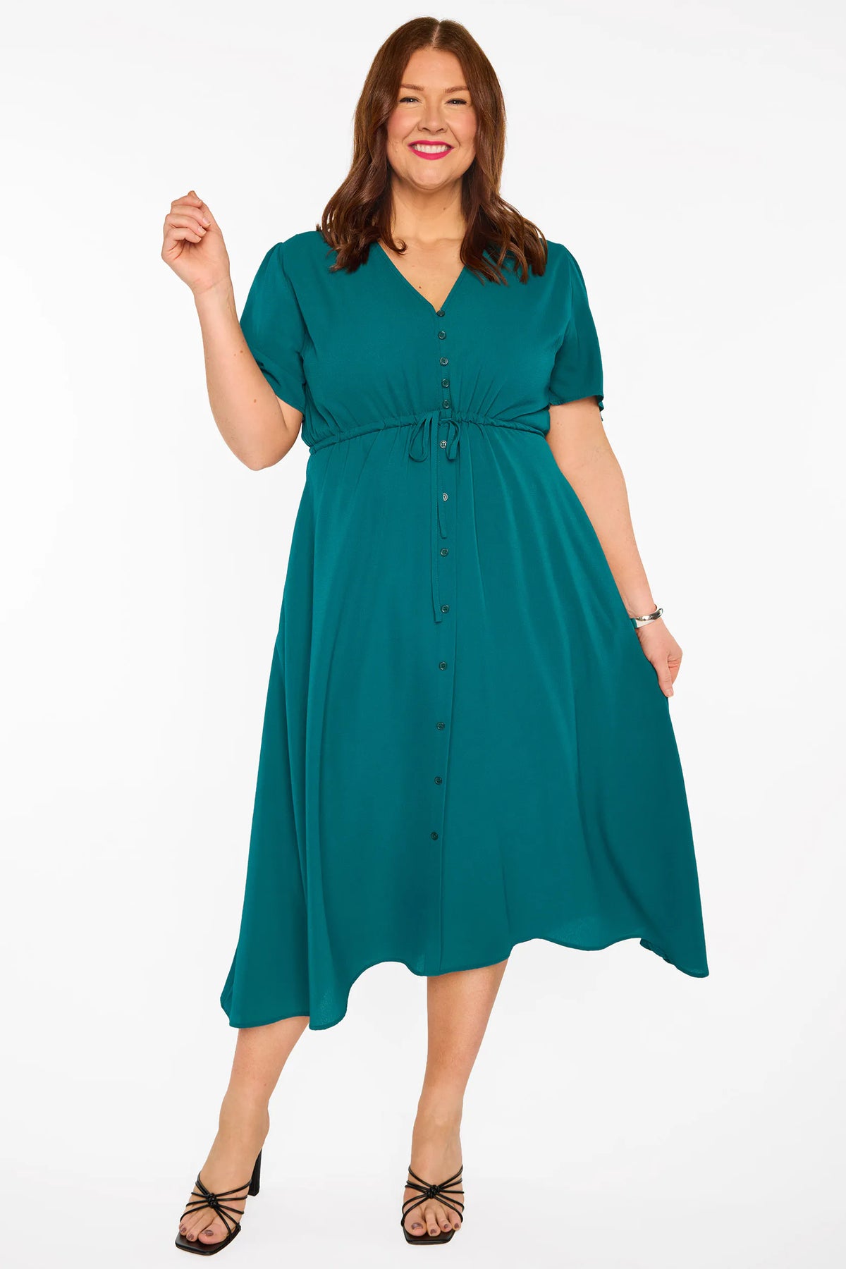 A woman modelling a teal green midi dress with short sleeves, a button-down front, and a tie waist, set against a plain white studio background.