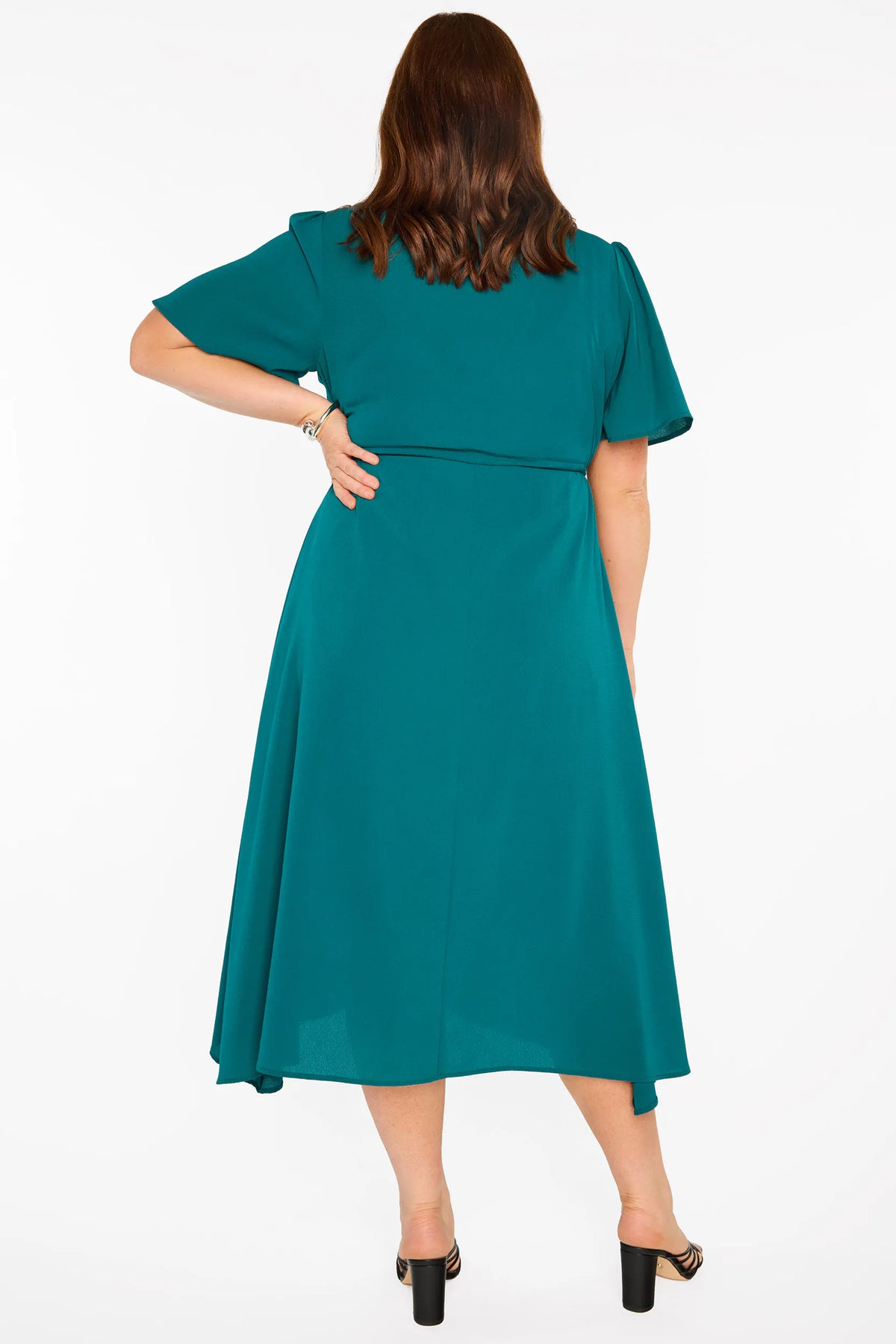 A woman modelling a teal green midi dress with short sleeves, a button-down front, and a tie waist, set against a plain white studio background.