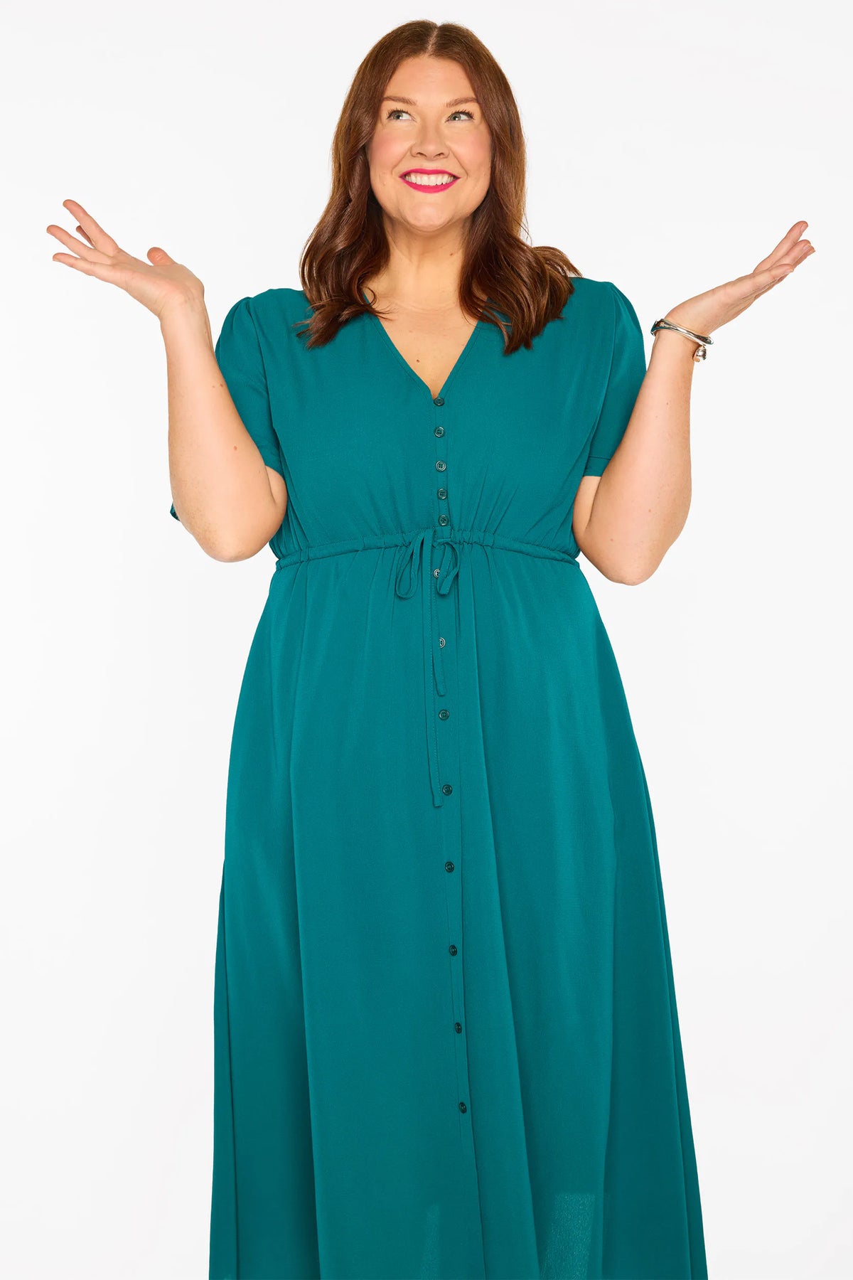 A woman modelling a teal green midi dress with short sleeves, a button-down front, and a tie waist, set against a plain white studio background.