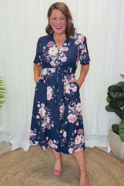Video of Woman wearing a Floral Dress with a navy base in front of a white background 